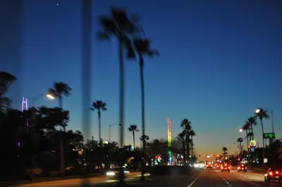 a city street with palm trees and traffic at night at Villas at Laguna Bay in Kissimmee