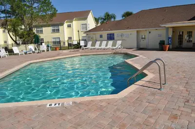 a swimming pool in a yard with chairs and a house at Villas at Laguna Bay in Kissimmee