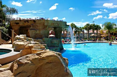 a swimming pool with a waterfall in a resort at Family 4-Bedroom Pool Home Near Disney World in Kissimmee
