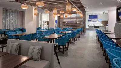 a dining room with blue chairs and tables at Holiday Inn Express & Suites Orlando At SeaWorld by IHG - With Free Shuttle Service to SeaWorld Parks in Orlando