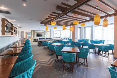 a dining room with blue chairs and tables at Holiday Inn Express & Suites Orlando At SeaWorld by IHG - With Free Shuttle Service to SeaWorld Parks in Orlando