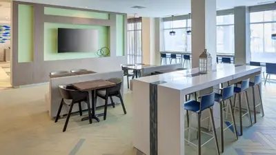 a lobby with a bar with stools and a tv at Holiday Inn Express & Suites Orlando At SeaWorld by IHG - With Free Shuttle Service to SeaWorld Parks in Orlando