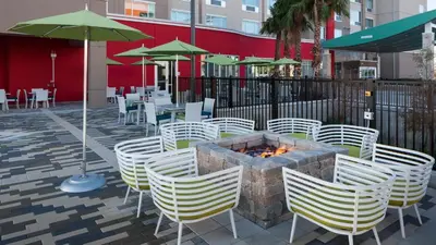 a patio with white chairs and a fire pit at Holiday Inn Express & Suites Orlando At SeaWorld by IHG - With Free Shuttle Service to SeaWorld Parks in Orlando