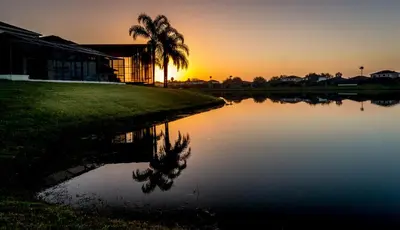 a sunset over a lake with a palm tree and a building at Suaimhneas in Kissimmee