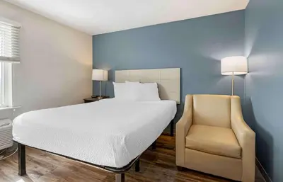 a bedroom with a bed and a chair at Extended Stay America Select Suites - Orlando - Airport in Orlando