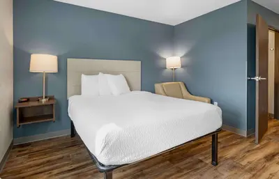 a large bed in a room with a blue wall at Extended Stay America Select Suites - Orlando - Airport in Orlando