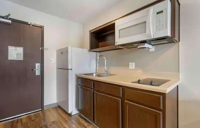 a kitchen with a sink and a microwave and a refrigerator at Extended Stay America Select Suites - Orlando - Airport in Orlando