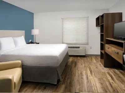 a hotel room with a bed and a television at Extended Stay America Select Suites - Orlando - Airport in Orlando