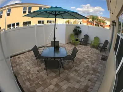 a patio with a table and chairs and an umbrella at Four Bedrooms Townhome 5126 in Kissimmee
