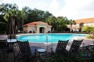 a pool with chairs and tables and a building at Four Bedrooms Townhome 5126 in Kissimmee