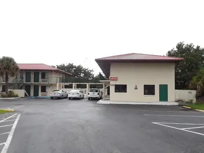 a parking lot with cars parked in front of a building at Riviera Motel in Kissimmee