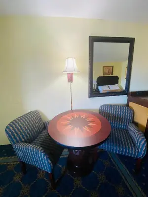 a room with a table and two chairs and a mirror at Maple Leaf Inn & Suites in Kissimmee