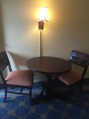 a table and two chairs and a lamp in a room at Maple Leaf Inn & Suites in Kissimmee