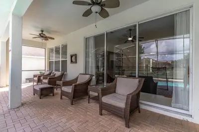 a screened in porch with chairs and a ceiling fan at 7741 Windsor Hills in Orlando