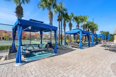 a group of blue umbrellas and tables and palm trees at 8965 Paradise in Kissimmee