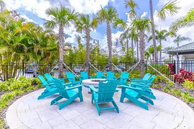 a group of blue chairs and tables on a patio with palm trees at 5036 105 Viz Cay in Orlando