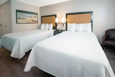 two beds in a hotel room with white sheets at Extended Stay America Suites - Orlando - Lake Buena Vista in Orlando