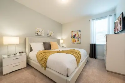 a bedroom with a white bed and a television at Groovy Mouse House with private pool in Orlando