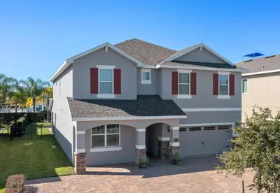 a white house with a garage at Beautiful Home With Private Pool, Media & Game Room Near Disney With Waterpark And Resort Access At Encore Resorts Reunion - 210Cl in Kissimmee