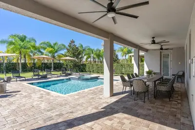 a patio with a table and chairs and a pool at Beautiful Home With Private Pool, Media & Game Room Near Disney With Waterpark And Resort Access At Encore Resorts Reunion - 210Cl in Kissimmee