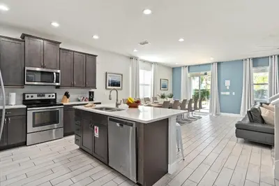 an open kitchen and living room with stainless steel appliances at Beautiful Home With Private Pool, Media & Game Room Near Disney With Waterpark And Resort Access At Encore Resorts Reunion - 210Cl in Kissimmee