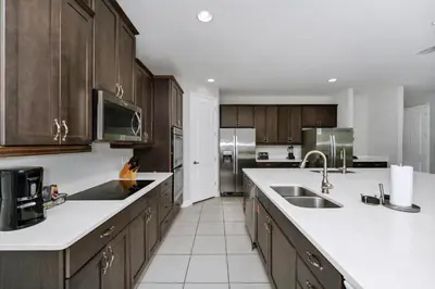 a kitchen with wooden cabinets and white counter tops at Vibrant Elite Home With Private Pool, Theater Room And Waterpark & Resort Access Near Disney At Encore Resort - 7605Mc in Kissimmee