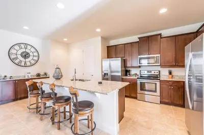 a kitchen with wooden cabinets and a island with bar stools at Elegant Home Near Disney With Private Pool And Waterpark & Resort Access At Encore Resorts Reunion - 391Fl in Kissimmee