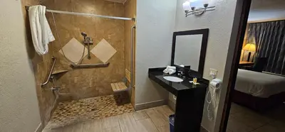 a bathroom with a shower with a sink and a mirror at Days Inn by Wyndham Orlando Downtown in Orlando