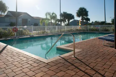 a swimming pool with a metal hand rail in it at Villas at Fortune Place in Kissimmee