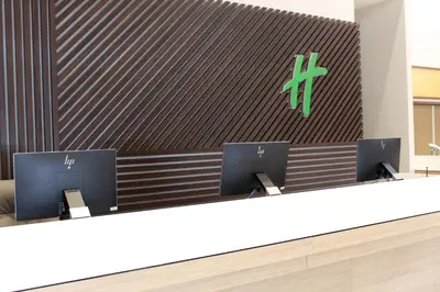 a reception desk with two monitors in front of a wall at Holiday Inn Orlando International Dr-ICON by IHG in Orlando