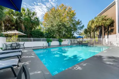 a swimming pool with a fence and trees at Best Western Plus Universal Inn - Free Shuttle to Universal Studios! in Orlando