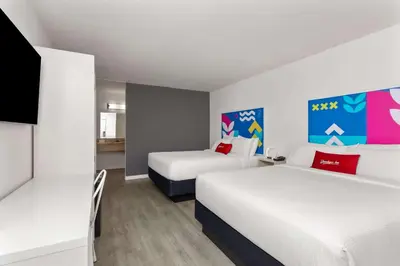 a hotel room with two beds and a desk at Baymont by Wyndham Orlando North Millenia in Orlando