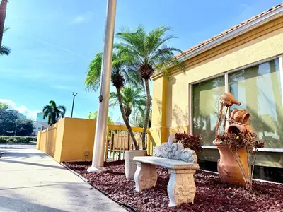 a bench and palm trees in front of a building at La Quinta by Wyndham Orlando Universal area - Free Shuttle to Universal in Orlando