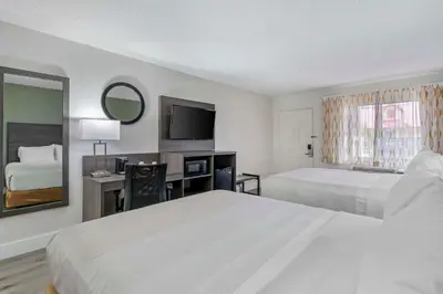 a hotel room with two beds and a desk with a mirror at Quality Inn & Suites Orlando East - UCF Area in Orlando