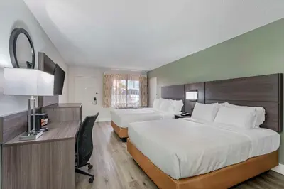 a hotel room with two beds and a desk at Quality Inn & Suites Orlando East - UCF Area in Orlando