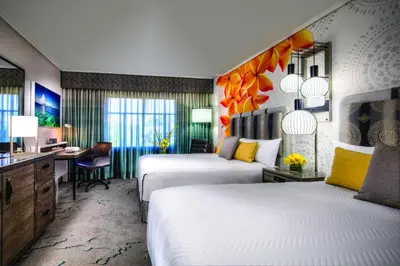 a hotel room with two beds and a desk at Universal's Loews Royal Pacific Resort in Orlando