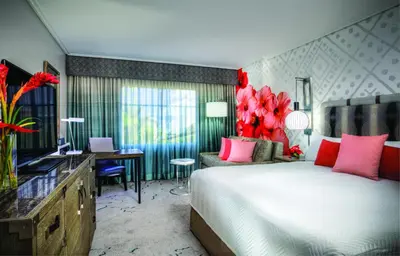 a bedroom with a bed and a desk and a room with at Universal's Loews Royal Pacific Resort in Orlando