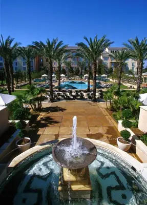 a fountain in the middle of a pool with palm trees at Universal's Loews Portofino Bay Hotel in Orlando
