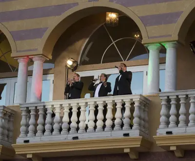three men in suits standing on a balcony at Universal's Loews Portofino Bay Hotel in Orlando