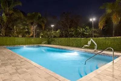 a swimming pool at night with a fence at Spark by Hilton Orlando Universal Boulevard in Orlando