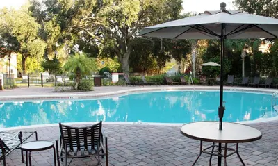a table with an umbrella next to a pool at Four Bedrooms Townhouse 5102 in Kissimmee