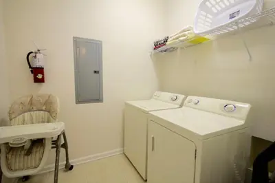 a laundry room with a washing machine and a chair at Shoreway House #231533 in Orlando