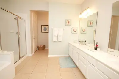 a white bathroom with two sinks and a mirror at Shoreway Condo #231521 in Orlando