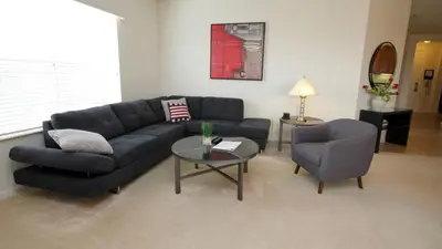 a living room with a black couch and two chairs at Shoreway Condo #231524 in Orlando