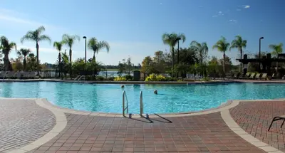 a large swimming pool with palm trees in a resort at Shoreway Condo #231520 in Orlando