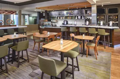 a restaurant with wooden tables and chairs and a bar at Courtyard by Marriott Orlando Airport in Orlando