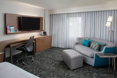 a hotel room with a couch and a desk with a television at Courtyard by Marriott Orlando Lake Buena Vista in the Marriott Village in Orlando