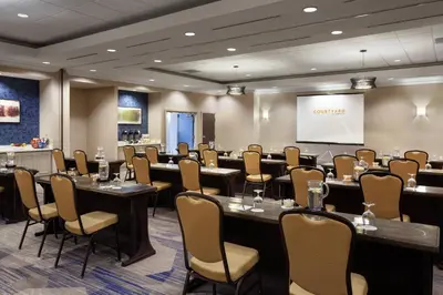 a conference room with tables and chairs and a screen at Courtyard by Marriott Orlando Lake Buena Vista in the Marriott Village in Orlando