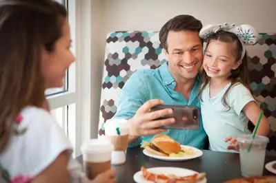 a man and a girl sitting at a table with a cell phone at SpringHill Suites by Marriott Orlando Lake Buena Vista in Marriott Village in Orlando