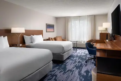 a hotel room with two beds and a desk at Fairfield Inn Orlando Airport in Orlando